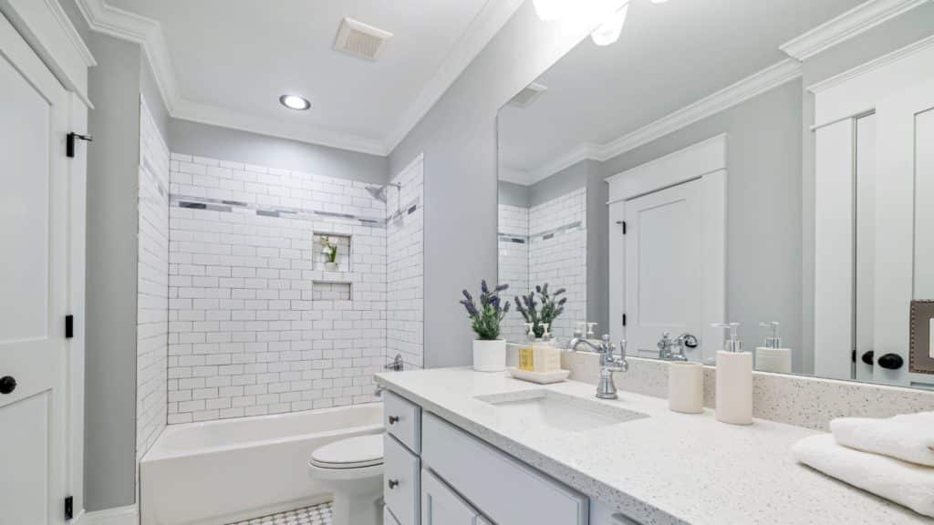 Bright white bathroom with vanity, tub-shower combination, and a toilet